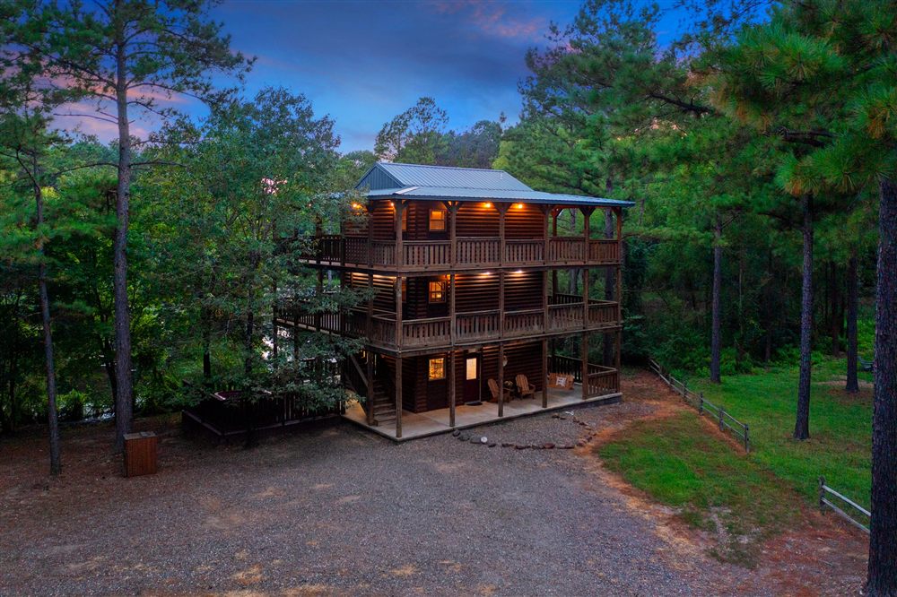 Lost Lake Treehouse, a three-story log cabin with wraparound decks, lit up at dusk